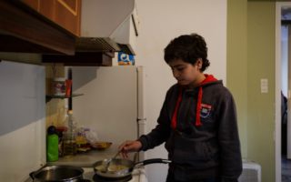 Fourteen-year-old Samir cooks in the kitchen of his family’s shared accommodation. © UNHCR/Achilleas Zavallis