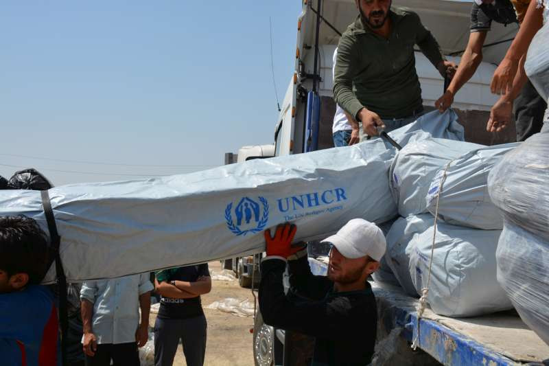 Workers unload trucks laden with hundreds of tents for families displaced by recent fighting in Iraq. Shelter is a priority for the displaced.