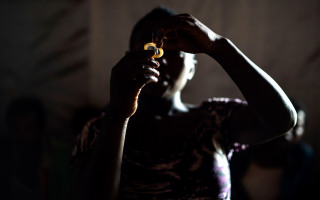 "Juliette" shows other sex workers how to use a condom during a meeting at Lushebere camp.