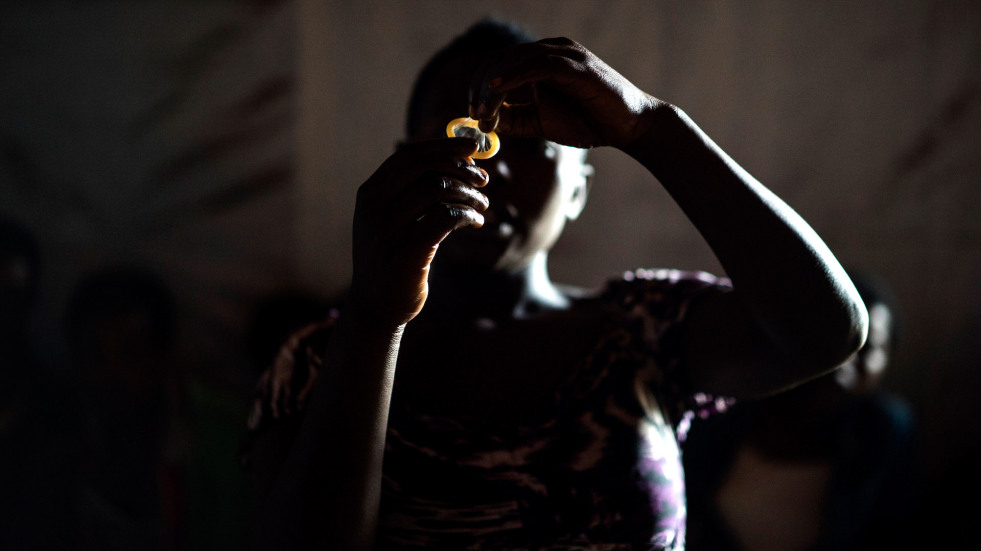 "Juliette" shows other sex workers how to use a condom during a meeting at Lushebere camp.