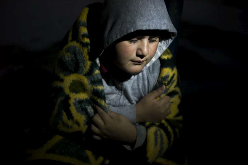 A displaced young Iraq boy in the north of the country uses a blanket to protect himself from the cold as a storm rages outside the half-built structure where he and his family have found shelter in Iraq's Kurdistan region.