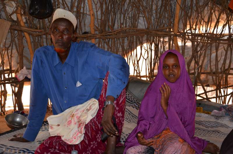 Hussein Farah and one of his 10 children sit in the shade of their shelter in Dagahaley refugee camp, Dadaab. He says it is tough to feed his children, even with full rations.