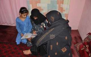 Aqeela teaching her daughters. She wants her school be upgraded to secondary school level so that her daughters and other students can continue studying.