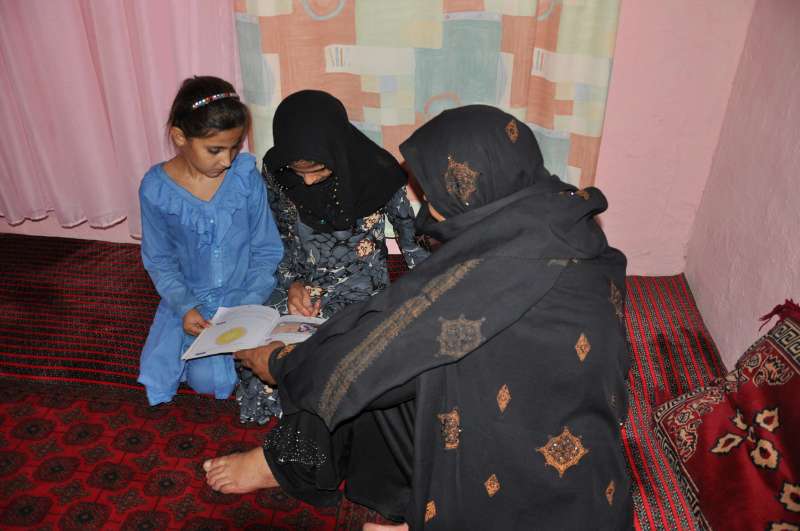 Aqeela teaching her daughters. She wants her school be upgraded to secondary school level so that her daughters and other students can continue studying.