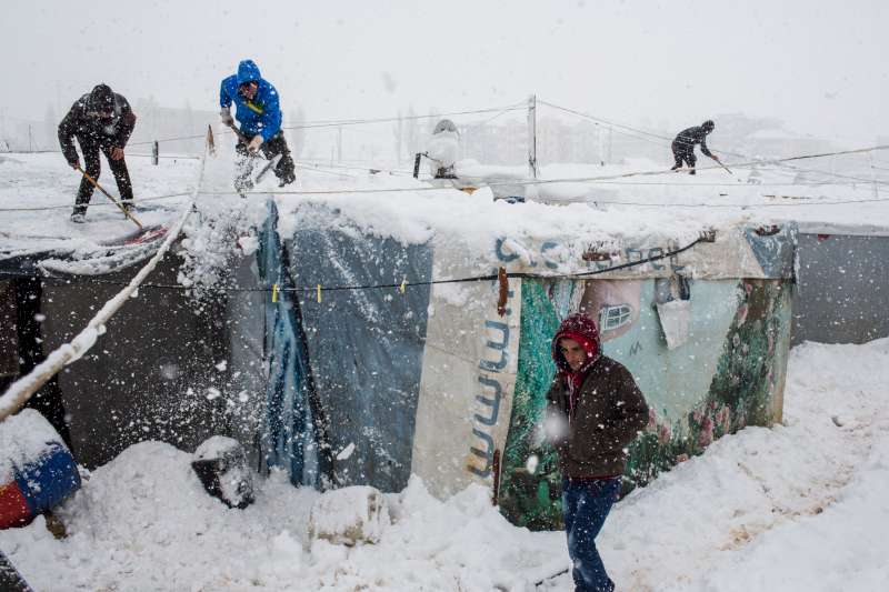 Des réfugiés syriens enlèvent la neige de leurs abris dans un camp dans la plaine de la Bekaa, au Liban pendant une tempête de neige. 