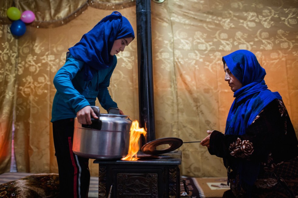 Aisha and her daughter Zam Zam, 12, prepare food in their shelter at an informal tented settlement in the Bekaa Valley. Outside, a snow storm whirls around the tent.