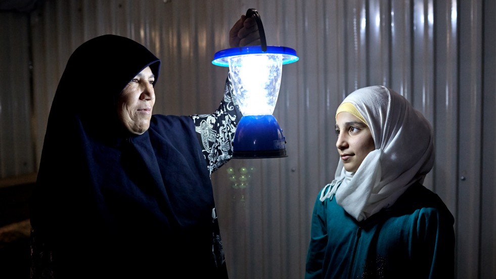 Um Fadi holds a solar-powered lamp beside her 13-year-old niece, Rama.