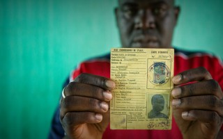 Oumar, who was at risk of statelessness, holds his father’s identity card from French colonial times.