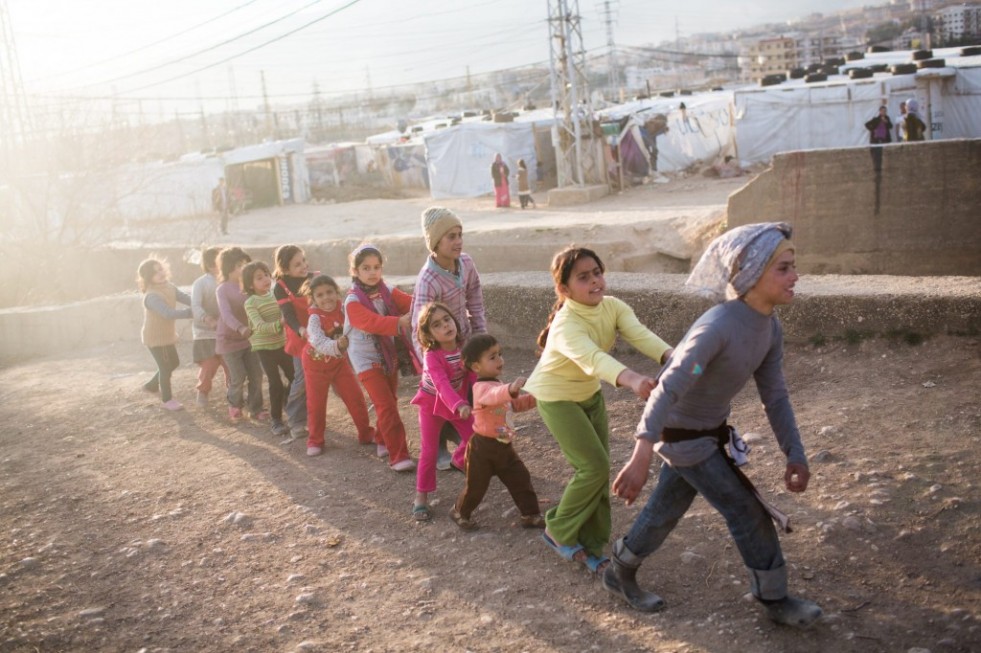 Hala, 11, leads young Syrian refugees, including her 10-year-old sister, Rahaf (5th from right), in a game at their settlement in the Bekaa Valley, Lebanon. 