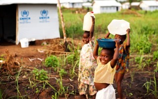 Three of Jean’s children carry water to their new home in Bili refugee camp, DRC.
