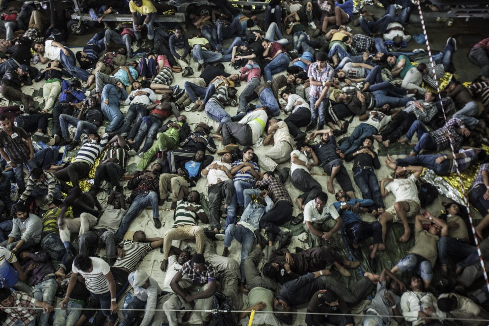 Single men sleep in a partitioned section of the San Giorgio military ship. On this particular night, 820 of them squeeze into this overcrowded area. Families and single women also have their own separate sleeping areas.