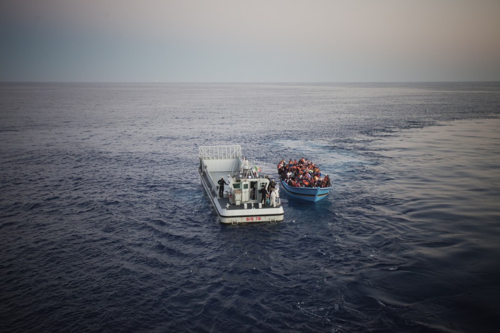 An Italian Navy rescue vessel, called the GIS, pulls up next to the first boat in order to transfer its desperate occupants. The GIS will then drive into the belly of the much larger San Giorgio, where people can safely disembark.