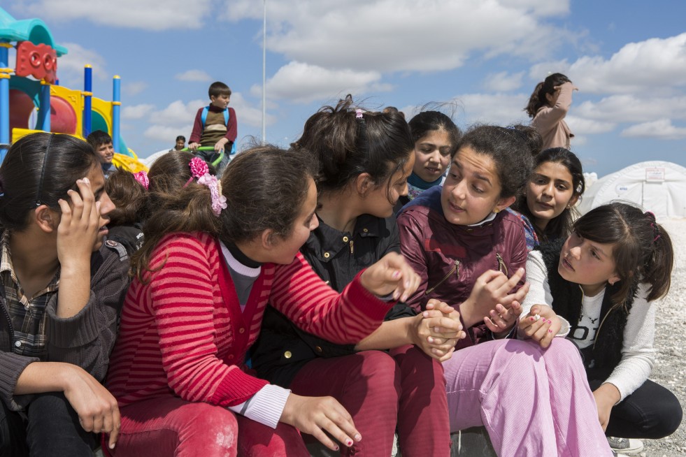 Ivra (with pink trousers) sits and talks with friends between classes in the playground of the school at Suruç refugee camp in Turkey. 