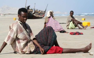 Exhausted survivors of the Gulf of Aden crossing wait for help on a beach in Yemen.