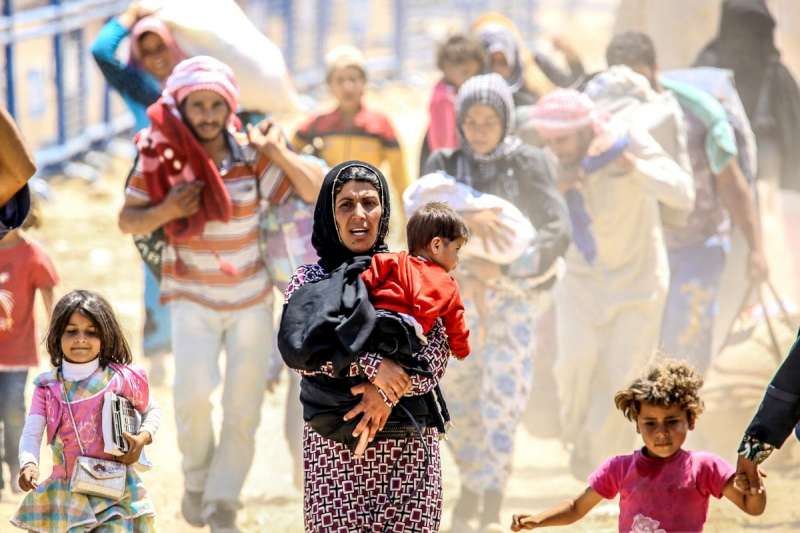 Syrians fleeing renewed fighting rush across broken down border fences at the Akcakale border crossing in Sanliurfa province in southern Turkey in June 2015.
