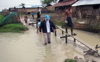 A UNHCR staff member wades through a flooded section of Nget Chaung camp for internally displaced people (IDP) in Pauktaw township, Rakhine State, on 2 August 2015. UNHCR was at Nget Chaung to assess the damage and identify needs caused by Cyclone Komen, which had swept through western Myanmar over the preceding few days.