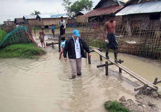 Un employé du HCR avance au milieu d'une zone inondée du camp de déplacés internes de Nget Chaung, dans la municipalité de Pauktaw, dans l'Etat de Rakhine. Le HCR évalue les dommages causés par le cyclone Komen et identifie les besoins.