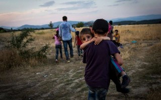 Un jeune réfugié syrien porte son frère pour passer la frontière entre la Grèce et l'ex-République yougoslave de Macédoine, près d'Eidomeni en Grèce, en juin 2015.