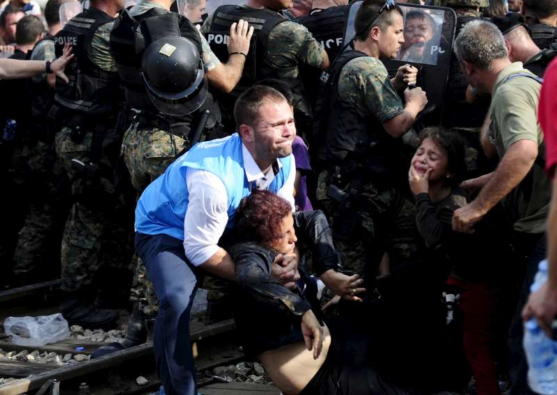 A UNHCR staff member assists a woman who collapsed at the border of Greece and FYR Macedonia on 21 August 2015.