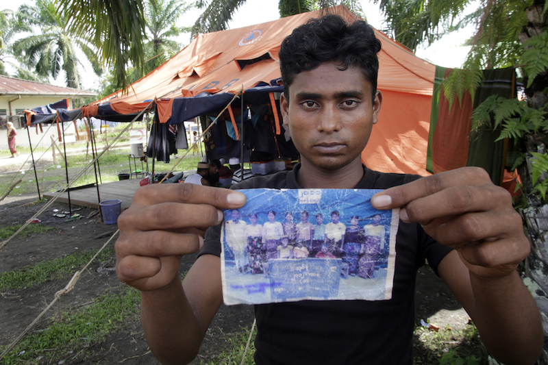 Roshid holds up a family photograph, which he carried with him throughout his journey on smugglers' boats from Myanmar to Indonesia. 