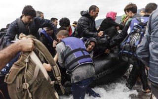 A group of refugees disembark an inflatable boat after reaching the Greek island of Lesvos.