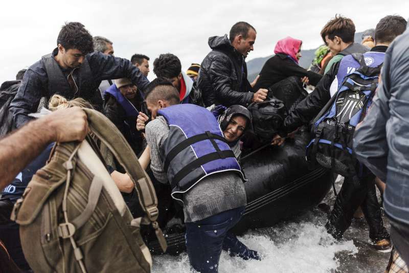 A group of refugees disembark an inflatable boat after reaching the Greek island of Lesvos.