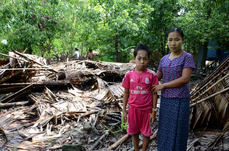 Ma Nge and her 10-year-old son stand outside the remains of their home in a small village in Ponnagyun township, Rakhine State. Cyclone Komen caused a tree to smash it down.