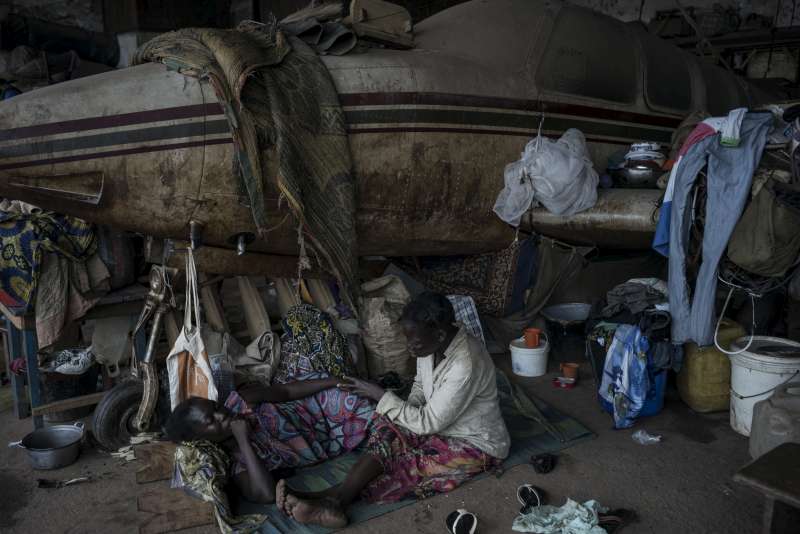 Des femmes déplacées se protègent contre la pluie dans le site pour déplacés internes de Mpoko situé près de l'aéroport international à Bangui.