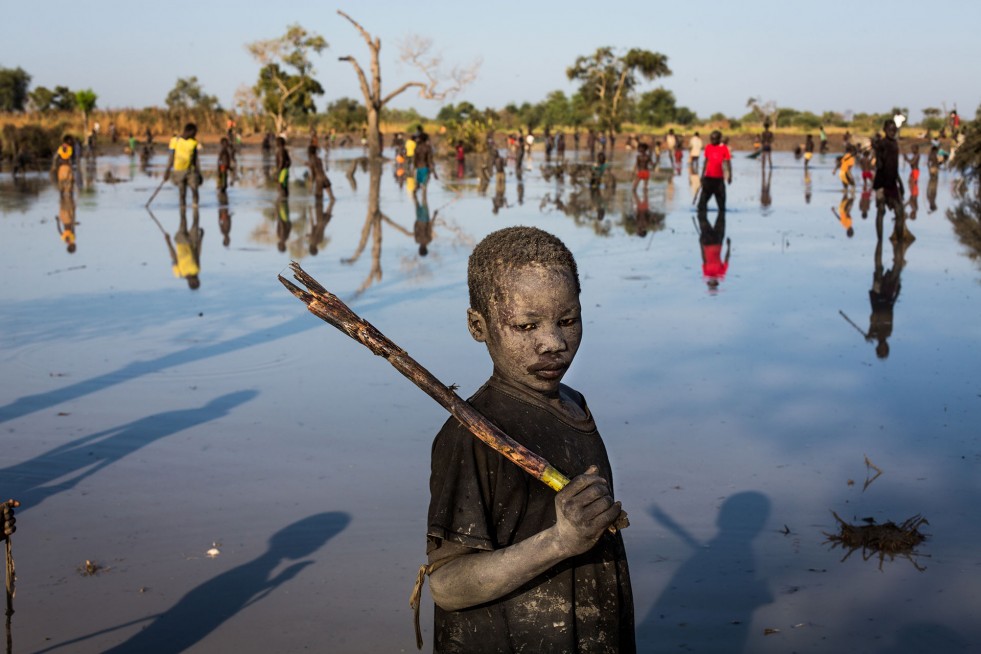 Yacob, a 10-year-old refugee, uses a stick to catch fish near Yida, South Sudan