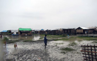 A man stands in a flooded section of Nget Chaung camp for internally displaced people in Pauktaw township, Rakhine State. UNHCR was at Nget Chaung to assess damage and identify needs after Cyclone Komen recently swept through western Myanmar.