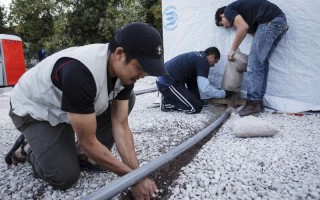 Des employés de la Bourse du Samaritain, un partenaire opérationnel du HCR sur l'île de Lesbos, installent un tuyau de drainage près d'une installation de latrines.
