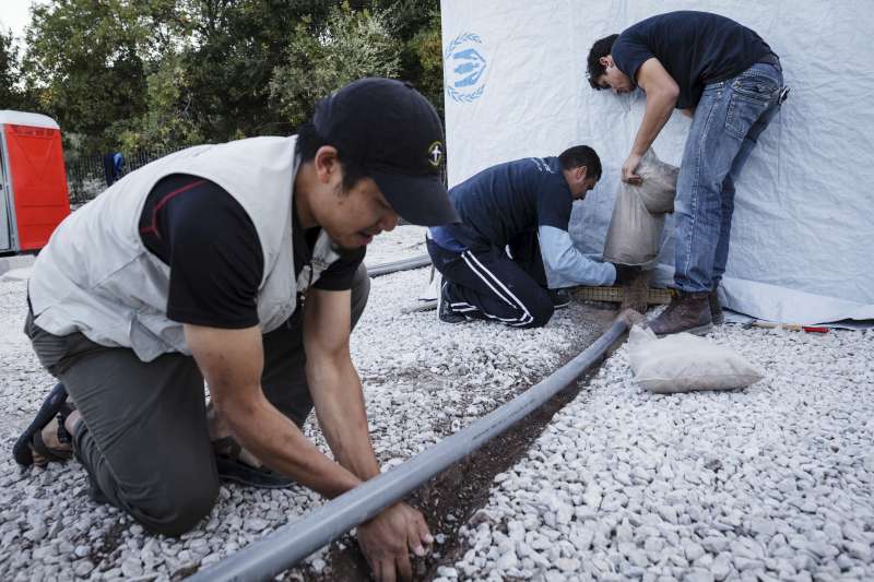 Des employés de la Bourse du Samaritain, un partenaire opérationnel du HCR sur l'île de Lesbos, installent un tuyau de drainage près d'une installation de latrines.