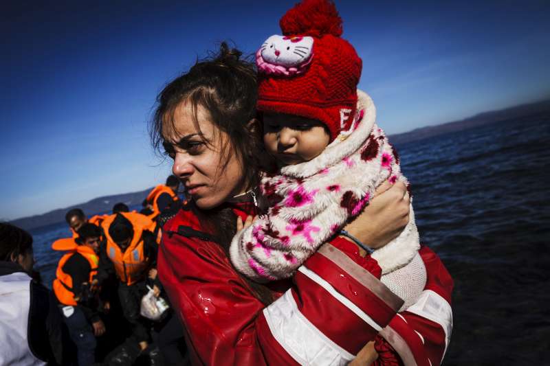 A volunteer on the Greek Island of Lesvos gathers a baby girl in her arms, moments after her family arrived in an inflatable boat.