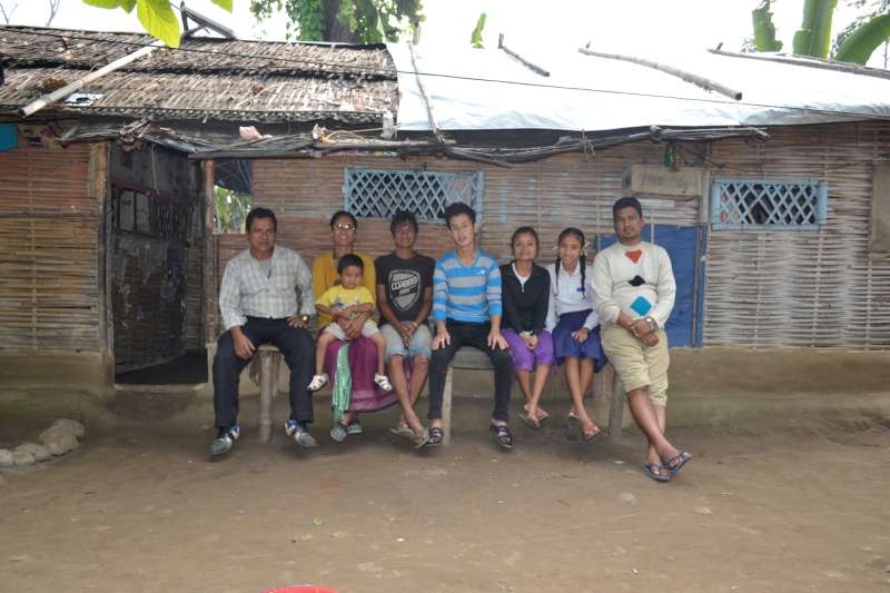 Bhutanese refugee Devi Maya Thapa (second left) sits on a bench with her family at a refugee camp in Nepal. She is the 100,000th Bhutanese refugee to be resettled.