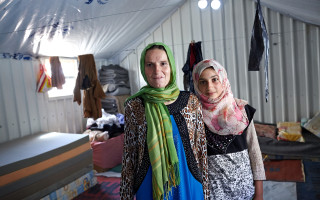 Syrian refugee Mona poses for a photograph with her daughter Bushra in their shelter at the Azraq refugee camp in Azraq, Jordan.