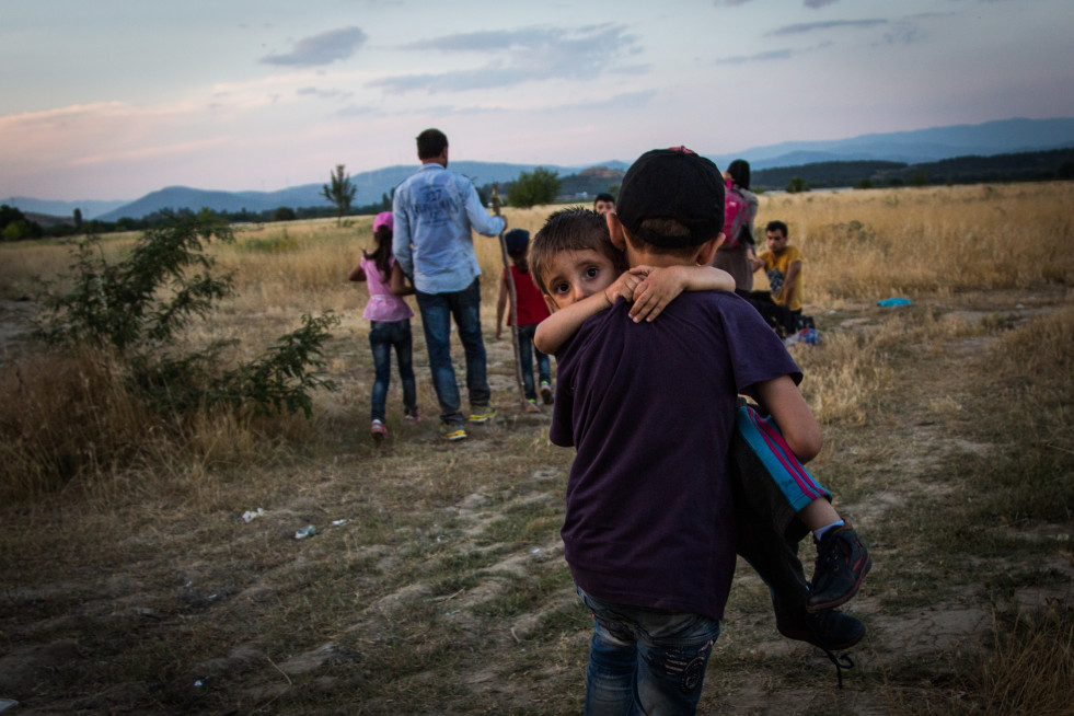 A young Syrian refugee carries his brother across the border between Greece and Macedonia, near Eidomeni, Greece.