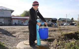Usmanov Abdulaziz, 12, fills a bucket with drinking water from a standpipe in Tashtak, Kyrgyzstan.
