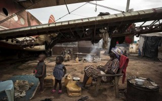 A displaced family finds shelter beneath the wing of an old aircraft at the airport in Bangui, Central African Republic.