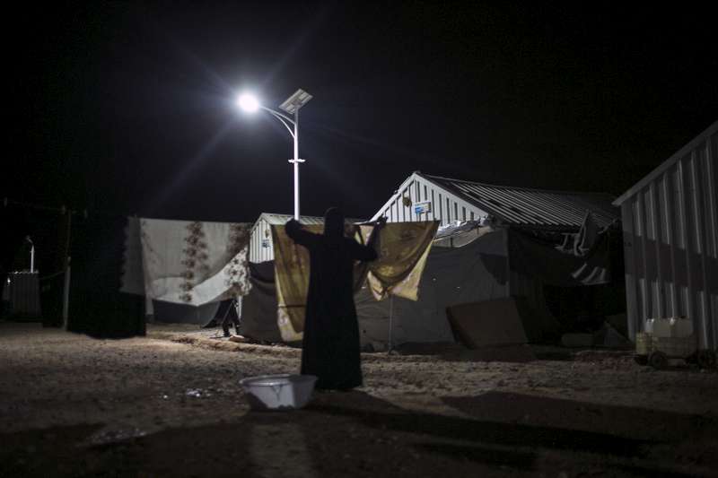 Une syrienne étend son linge à la lumière d'un réverbère solaire dans le camp de réfugiés d'Azraq en Jordanie.
