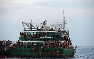 Refugees gather supplies airdropped to a fishing boat adrift in the Andaman Sea.