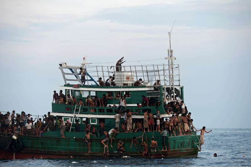 Des réfugiés à la dérive dans la mer d'Andaman recueillent de la nourriture larguée par un bateau de pêche.
