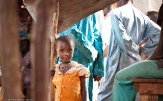 A refugee girl from the Central African Republic at the Mbile site in Cameroon walks through the market on 9 January 2015