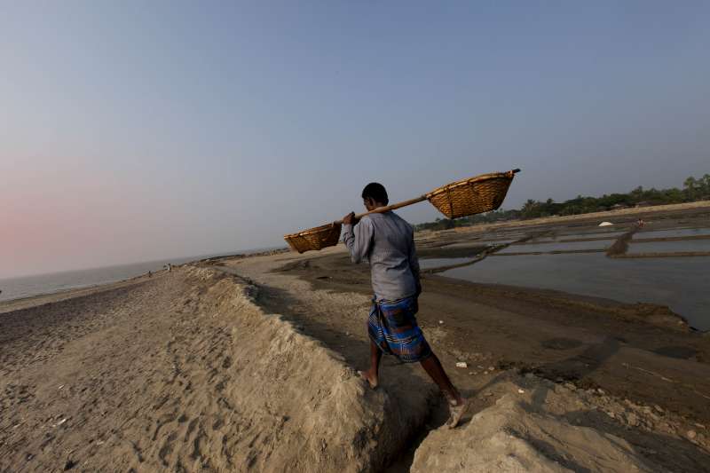 An unidentified man crosses the barren salty landscape on Kutubdia Island, Bangladesh.