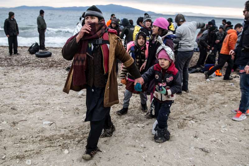 A family of refugees walk along the beach after landing on the Greek island of Lesvos in January 2016.