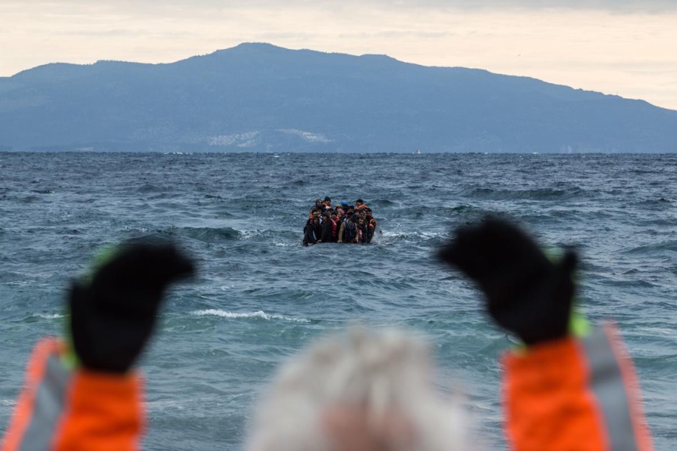 A volunteer beckons to a boatload of refugees arrives at the Greek island of Lesvos. UNHCR/Hereward Holland