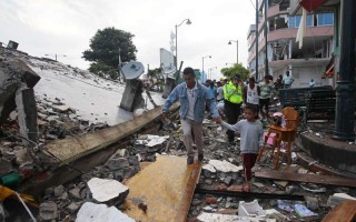 People walk among the debris of a collapsed building in the town of Pedernales, Ecuador, following a 7.8 magnitude earthquake