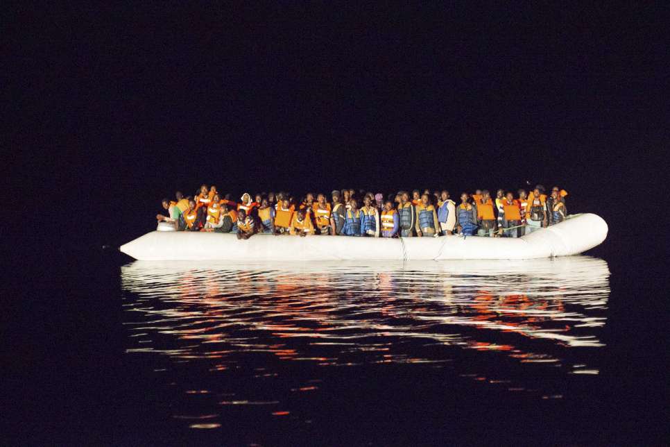 A boat filled with refugees and migrants crossing the Mediterranean floats off the coast of Italy. © Italian Navy/Masimo Sestini