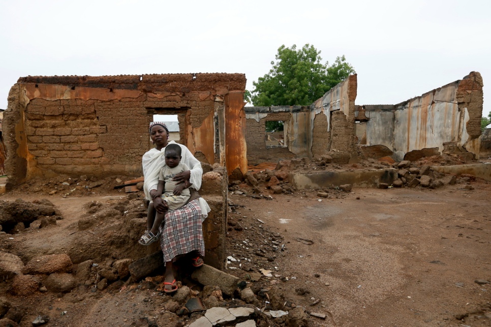 Des rapatriés nigérians assis devant une maison détruite par Boko Haram à Garaha, dans l’Etat d’Adamawa, au Nigéria, en mai 2016. © HCR/George Osodi