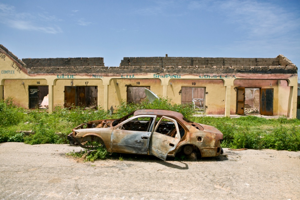 A burned out car lies in a street of destroyed homes in Gwoza, Nigeria, recently liberated by Nigerian armed forces. © UNHCR/Hélène Caux