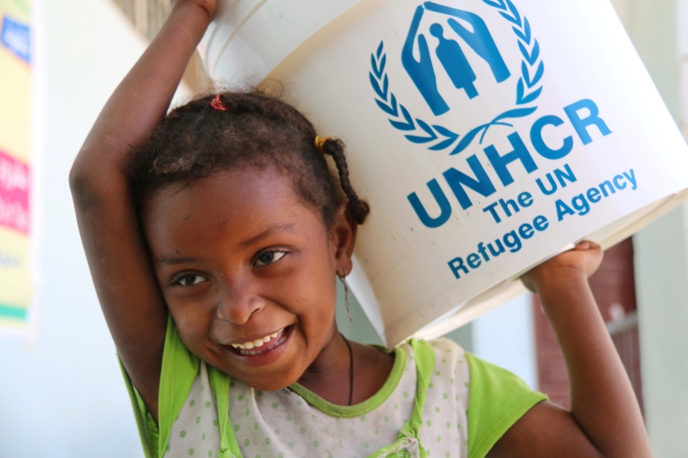 Firial (age 8) helping her father Ali collect goods during the aid distribution in Al Hagri school, Al Mudafar district, Taizz. © UNHCR/Mohammed Al Hasani